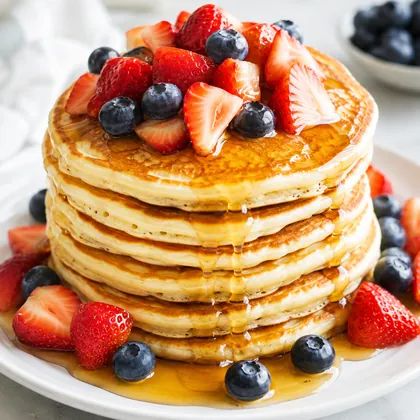 Pilha de panquecas com frutas vermelhas e mel escorrendo