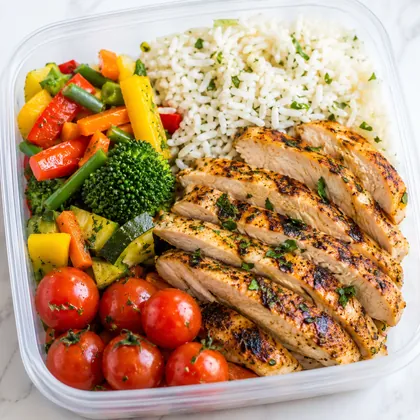 Marmita montada com frango fatiado, arroz e legumes coloridos